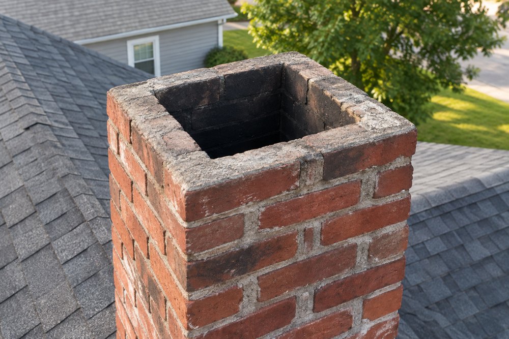 Uncapped brick chimney flue on a Northern Virginia house, a common raccoon entry point